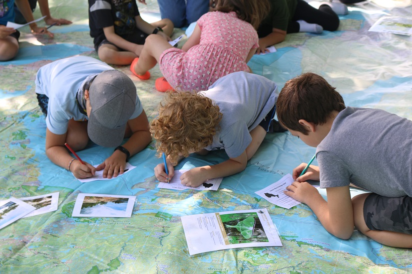Students writing on cards on map.