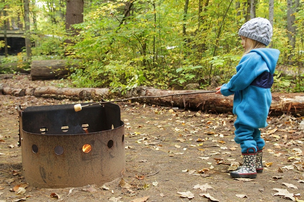 child roasting marshmallow over campfire