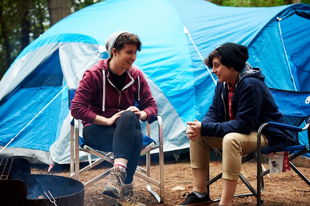 two people sitting on camp chairs in front of tent