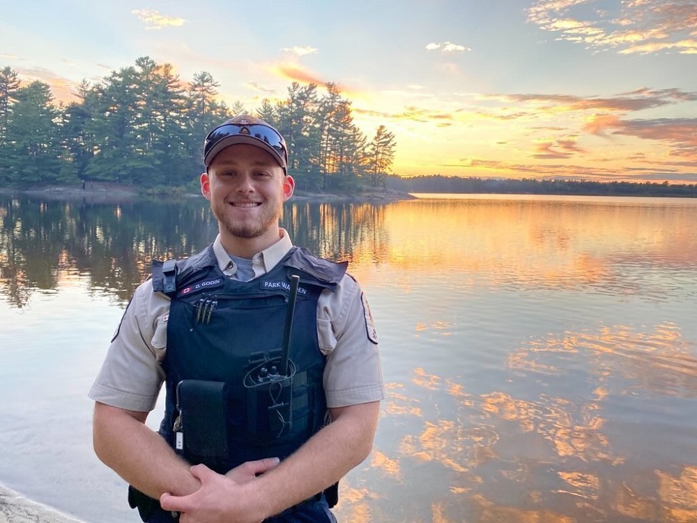 warden standing in front of lake at sunset