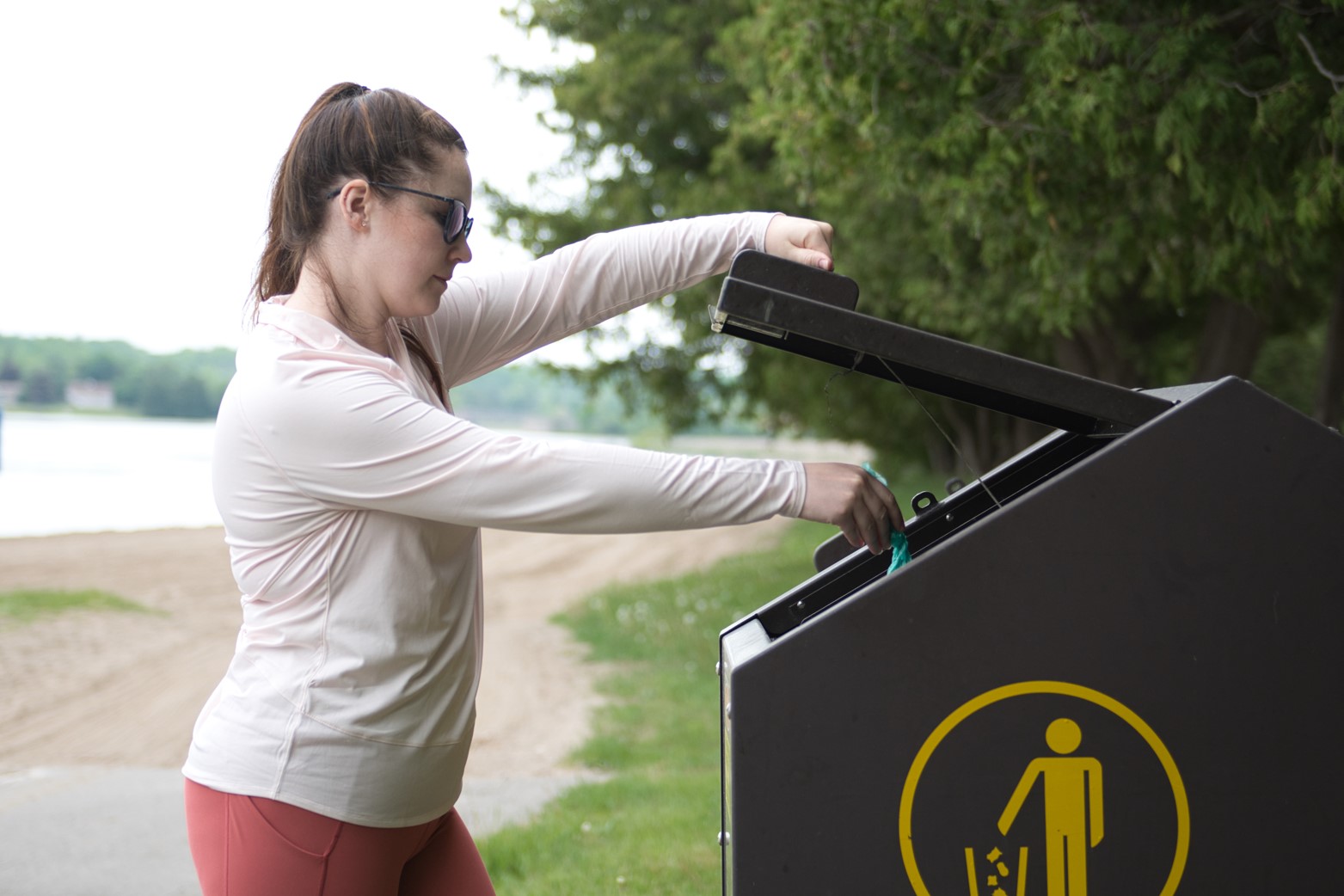 Woman throwing dog waste into an animal-proof waste bin
