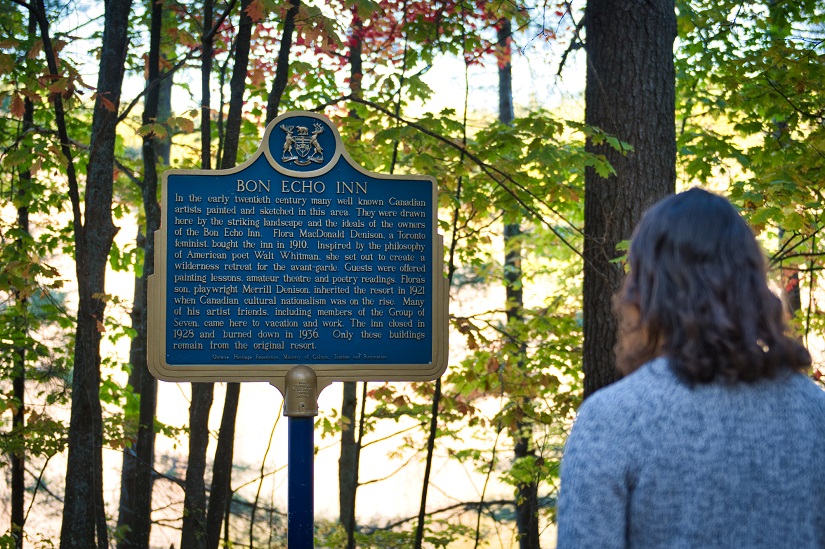 Un visiteur lisant une plaque historique dans la forêt.