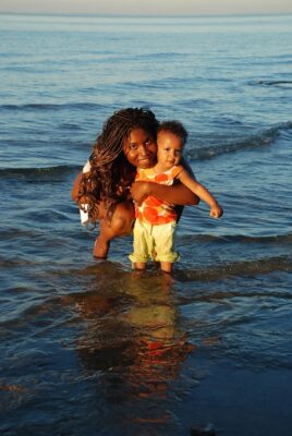 mother and child standing in shallow water of lake