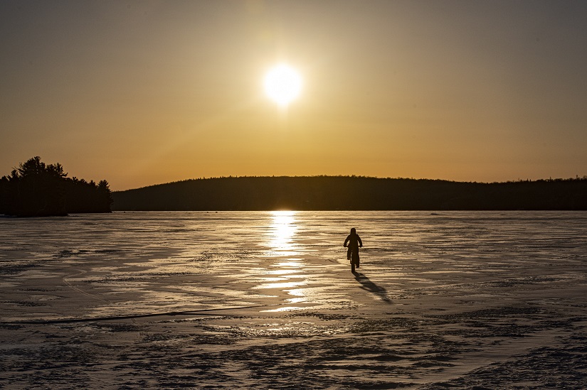 Fat biker on frozen lake with sunset.