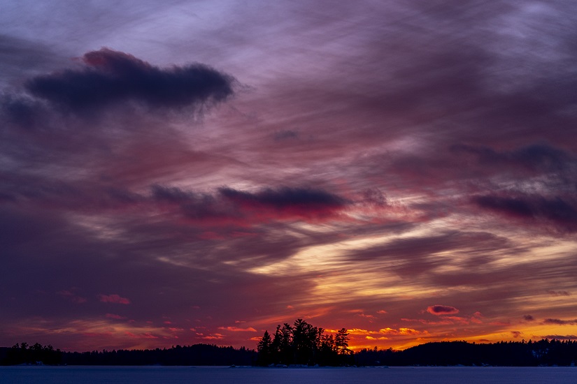 Red and purple sunset over snow-covered lake.
