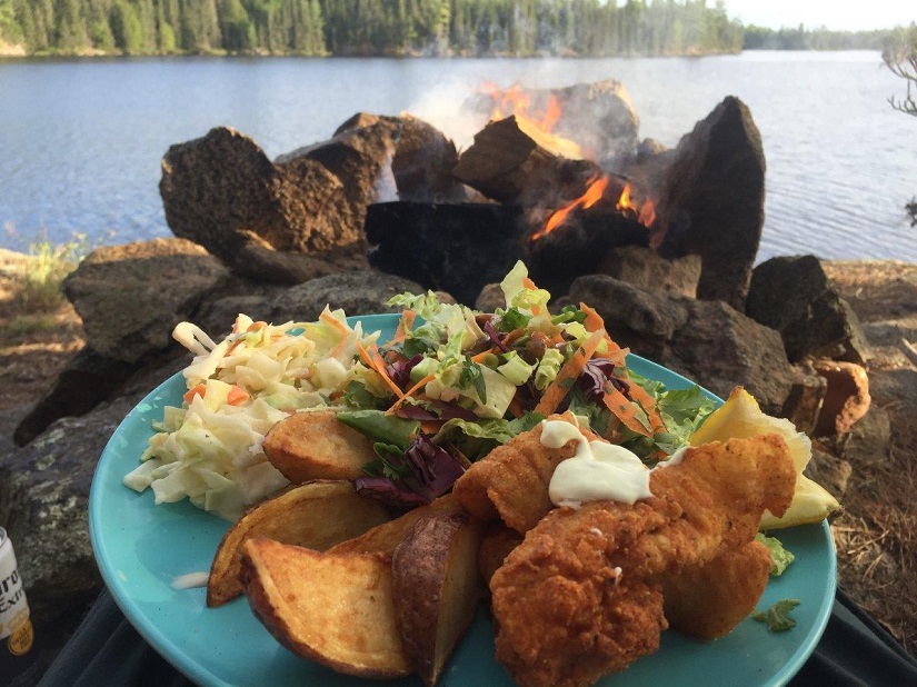 Fish fry on a plate in front of lake. 