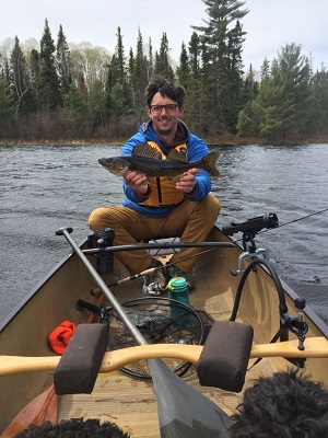 Angler in canoe holding up a walleye. 