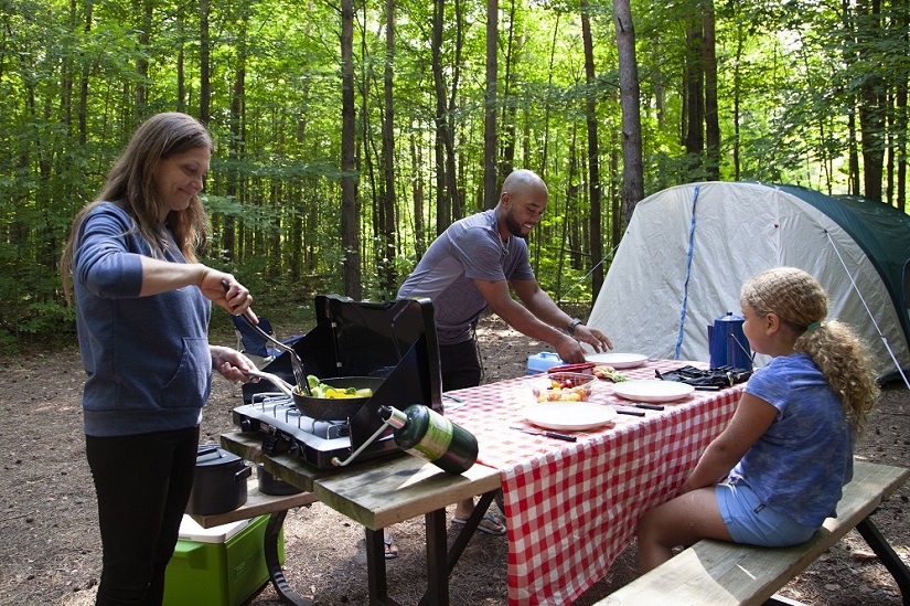 Family preparing meal on campsite. 