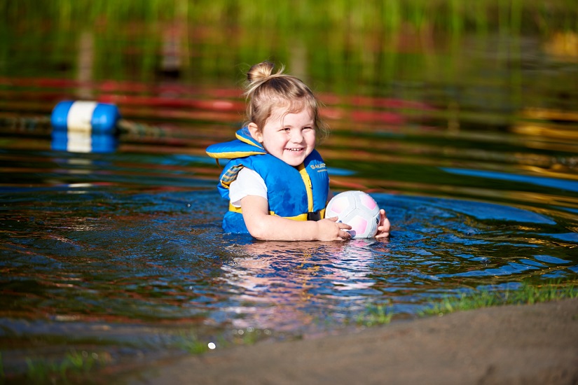 Enfant jouant dans l’eau, portant un gilet de sauvetage.