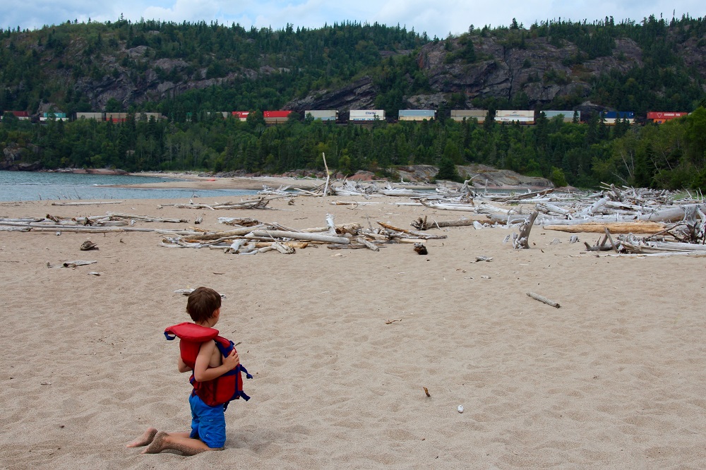 child watching train pass on beach