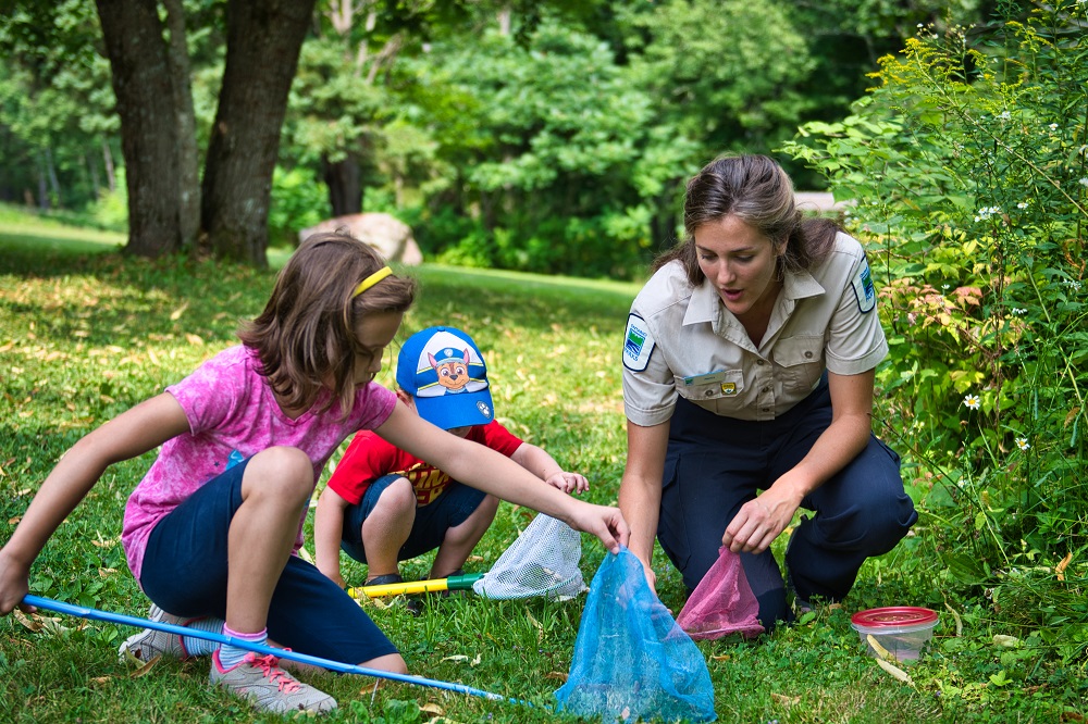 Une employée du programme Découverte avec des enfants tenant des filets à insectes