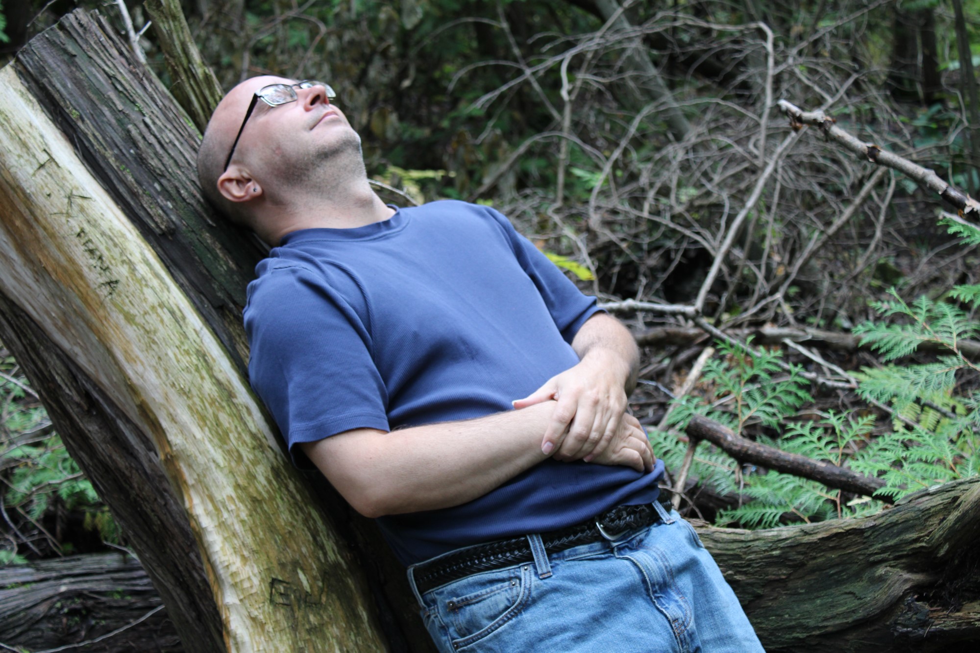 Un homme se relaxant contre un arbre, les yeux fermés