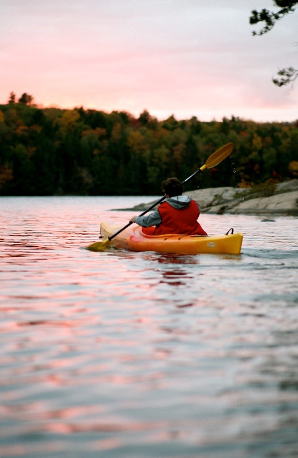 person paddling in kayak at sunset