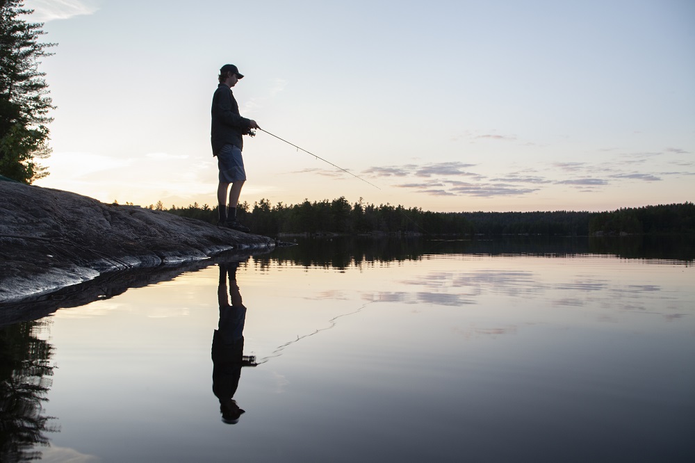 man fishing on lake from shore