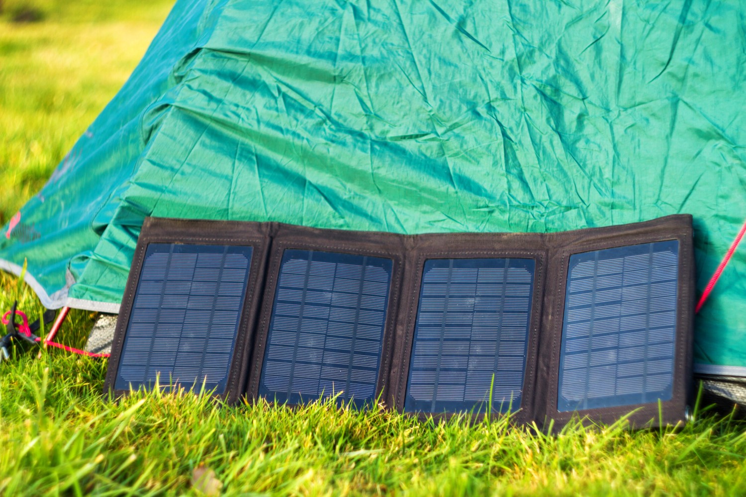 A row of small black solar panels leaning against the side of a green tent