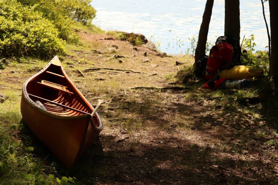 A canpe resting on the edge of a lake with a trekking backpack off to the side