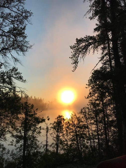 sun shining through fog on lake