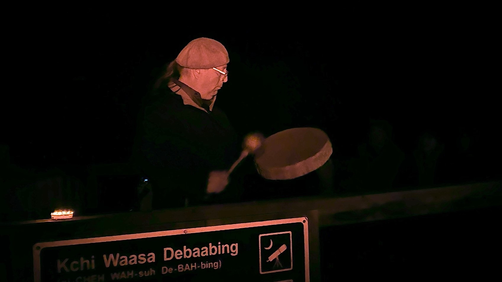 man playing drum in front of sign
