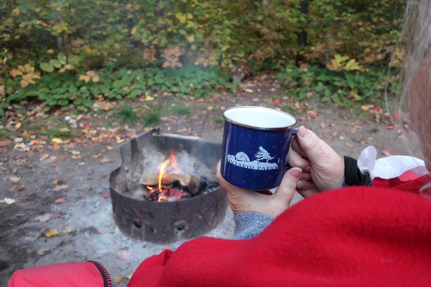 hands holding OP mug in front of campfire