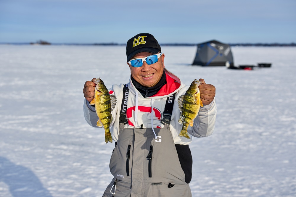 ice fisher holding two fish