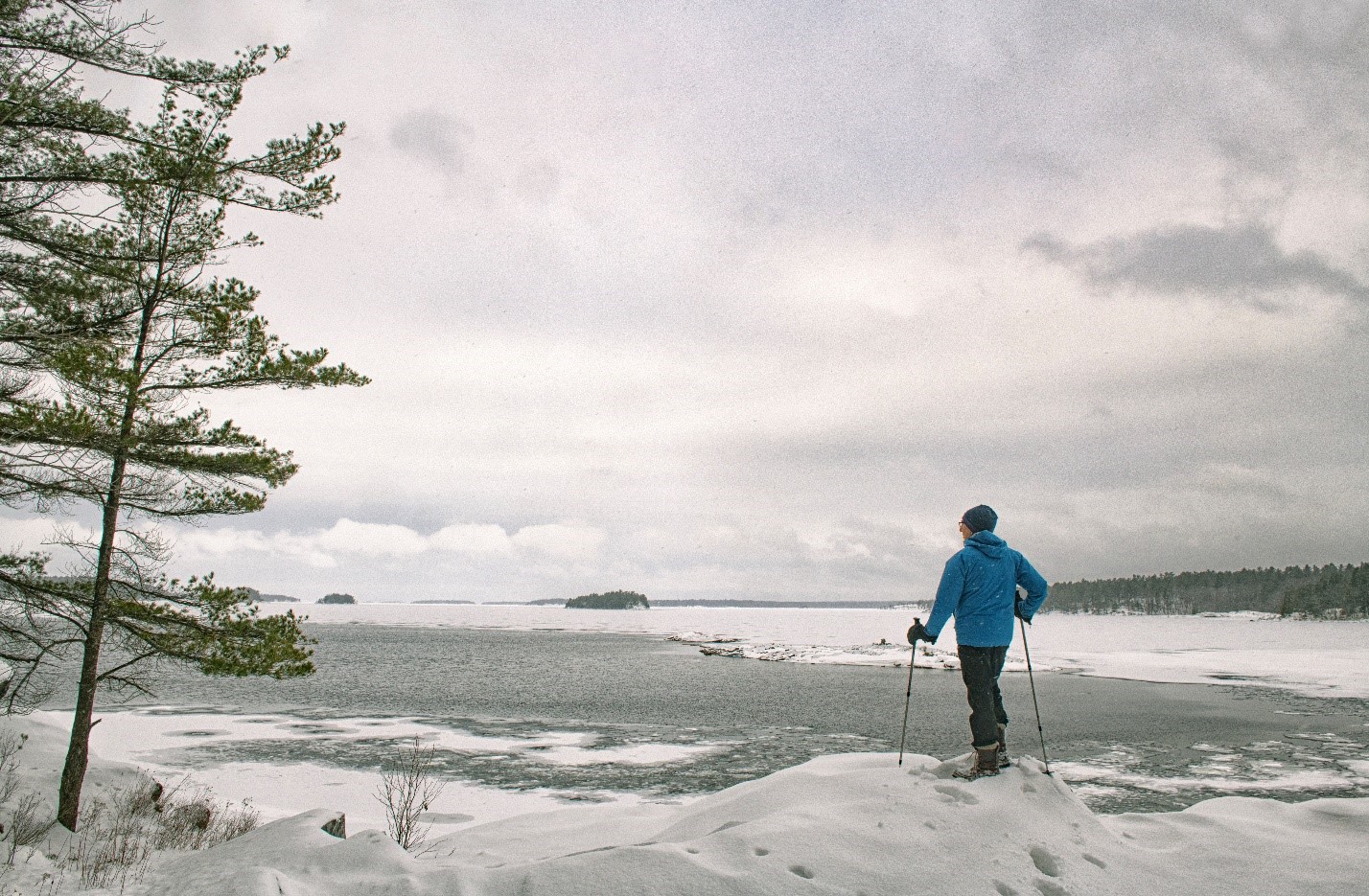 person looking out at partially frozen lake