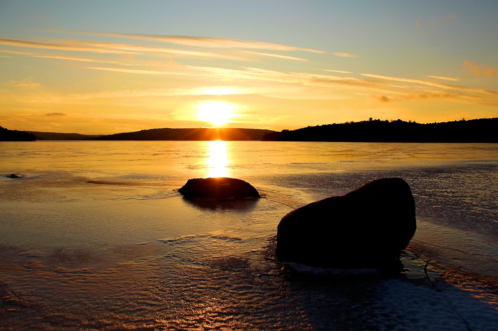 sun setting over frozen lake