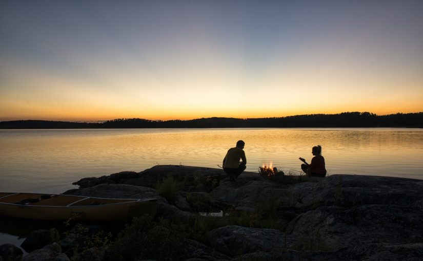 Des campeurs assis sur le rivage au coucher du soleil