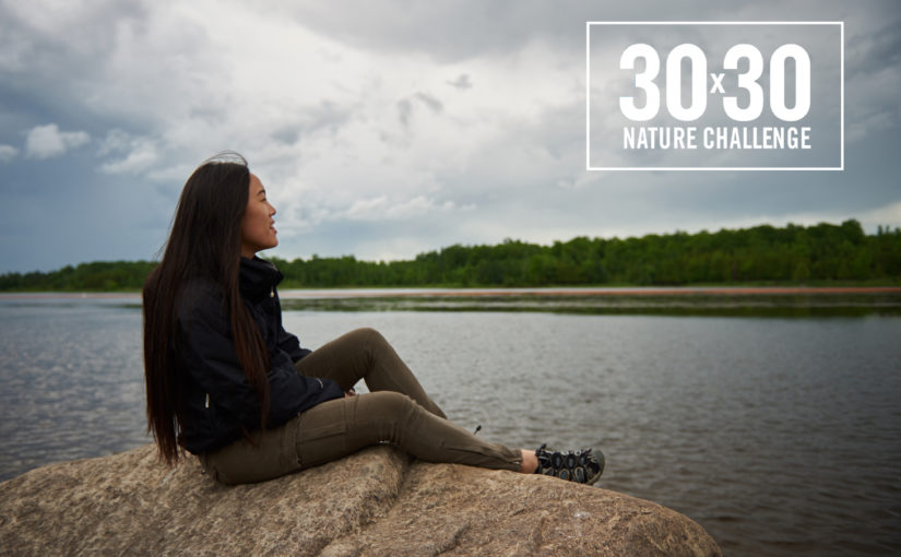 Photo d’une femme assise sur une roche près de l’eau avec le logo du Défi 30x30