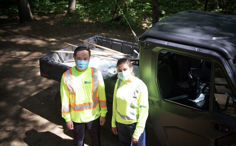 Deux membres du personnel devant un véhicule tout terrain utilitaire (VTTU).