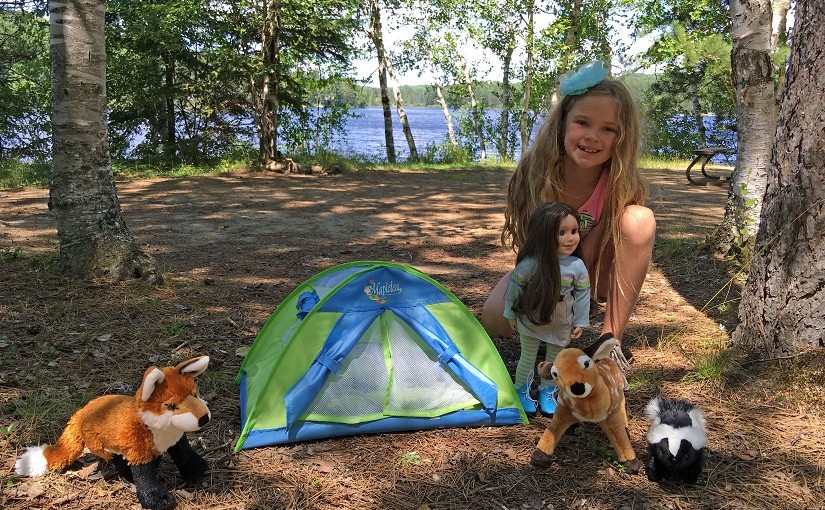 girl and doll on campsite