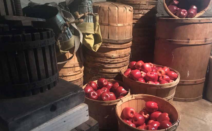 Three baskets of apples in the foreground of other harvest materials