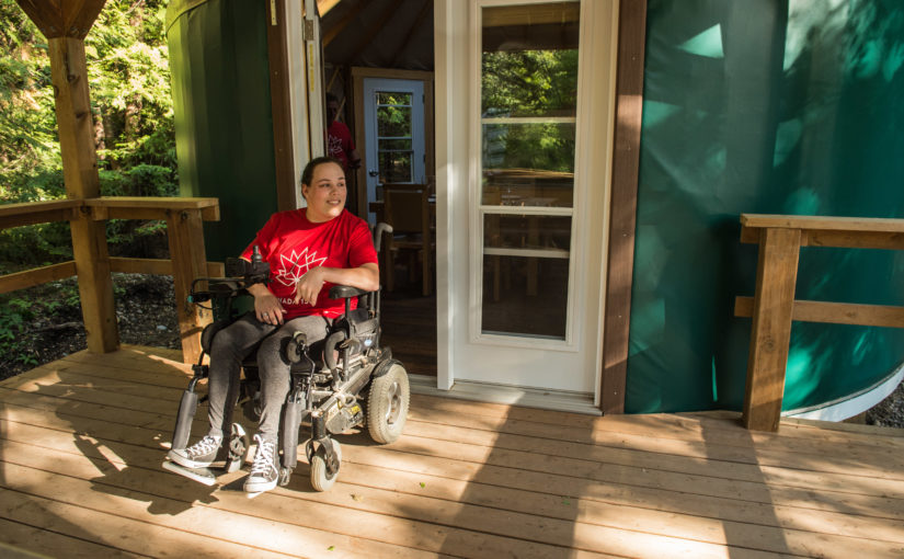 Person in wheelchair on yurt deck.