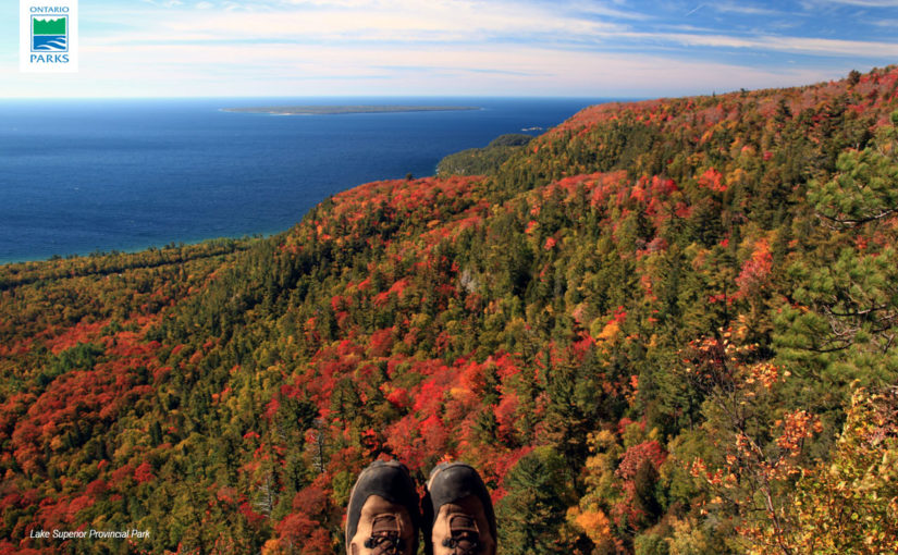 hiking boots atop a lookout. View of fall foliage and Lake Superior