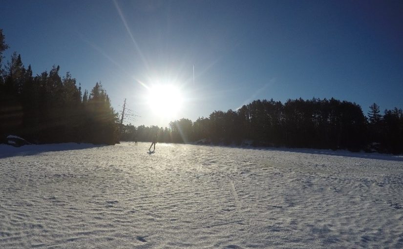 sunshine on snowy lake with skier