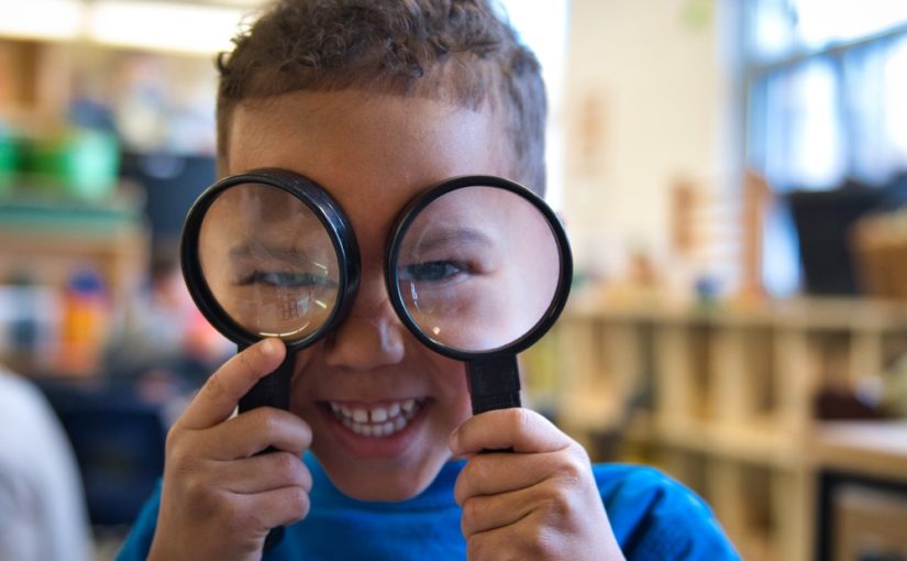 child holding up magnifying glasses to face