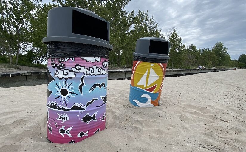 Brightly painted garbage cans on a beach.